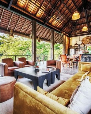 Relax in this charming outdoor seating area with sofas, chairs, and a coffee table, surrounded by lush greenery.