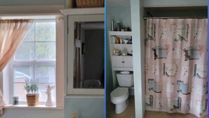 Un baño con inodoro, repisas con artículos de aseo y cortina de ducha con estampado floral.