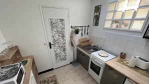 Eine kleine Küche mit Mikrowelle, Herd, Spüle und kleinem Kühlschrank.