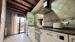Una cocina con salpicadero de azulejos, horno empotrado, microondas y cafetera.