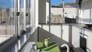 Une cuisine moderne avec de grandes fenêtres, un coin repas avec une nappe verte et une vue sur les montagnes.