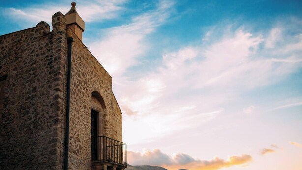 Un bâtiment en pierre doté d’un balcon, avec un ciel dégagé.