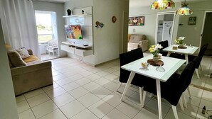 Een moderne woonkamer met een bank, televisie en een eethoek met stoelen en een tafel.