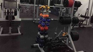 Een fitnessruimte met diverse trainingsapparaten, waaronder gewichten, barbells en halterplaten.