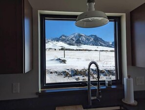Ein Badezimmer mit großem Fenster und Blick auf schneebedeckte Berge.