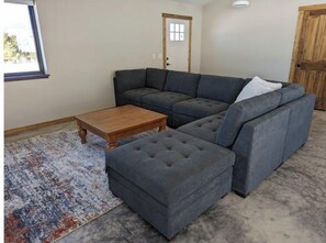 A living room with a sectional sofa, a wooden coffee table, and a patterned rug.