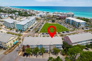 An aerial view of a coastal residential area with multi-story buildings, a parking lot, and a beachfront.