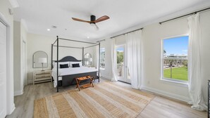 A four-poster bed in a bedroom with a view of a building and a balcony. - Gulf Place Spires #7B by Southern Vacation Rentals (Santa Rosa Beach)