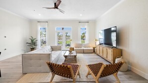 A spacious living room with a large TV, comfortable seating, and a view of the outdoors. - Gulf Place Spires #7B by Southern Vacation Rentals (Santa Rosa Beach)