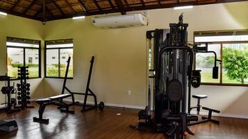 A gym with various exercise equipment, large windows, and a wooden floor.