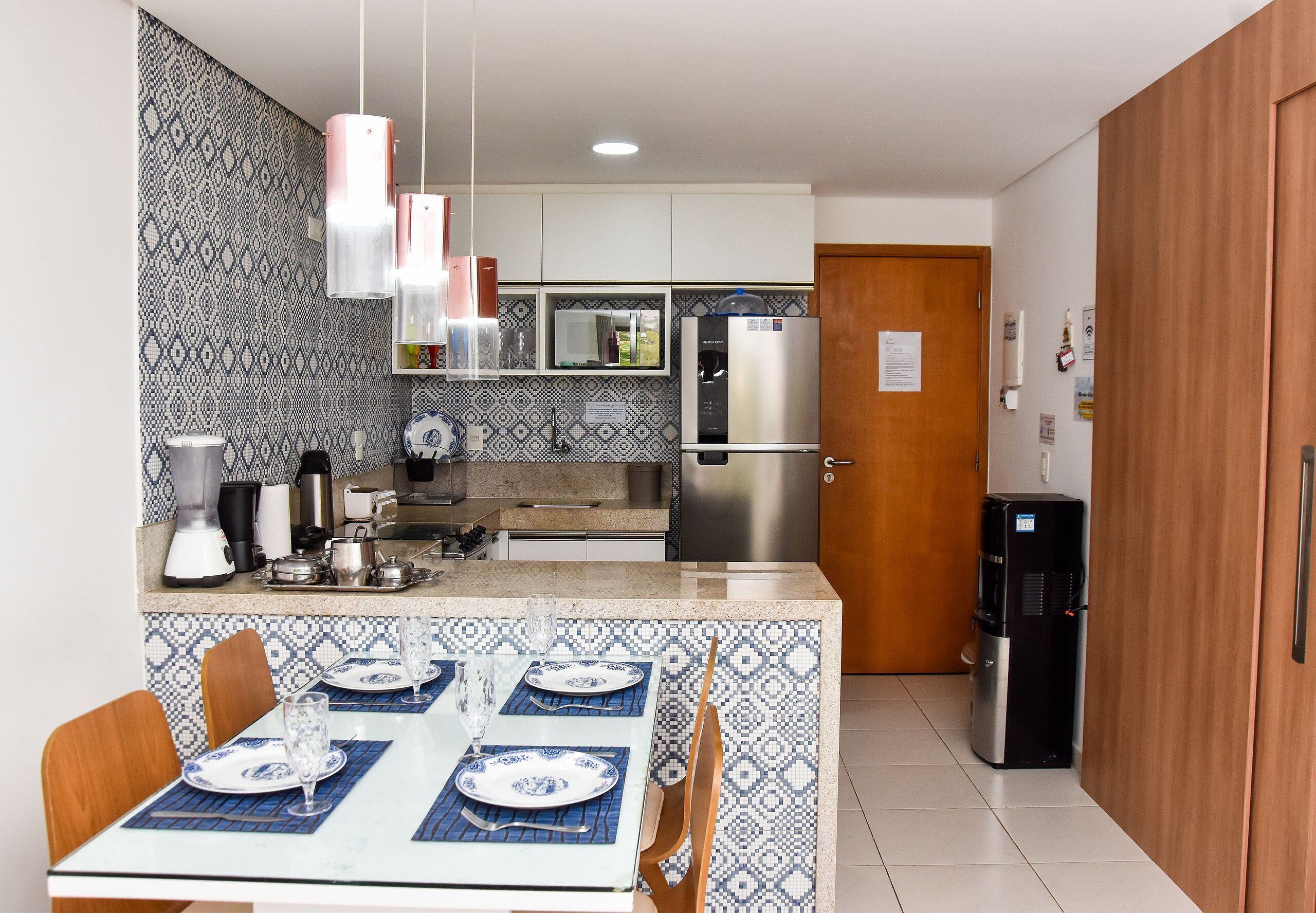 Een moderne keuken met een eethoek, met een centraal keukenblok, roestvrijstalen apparatuur en een decoratieve spatwand.