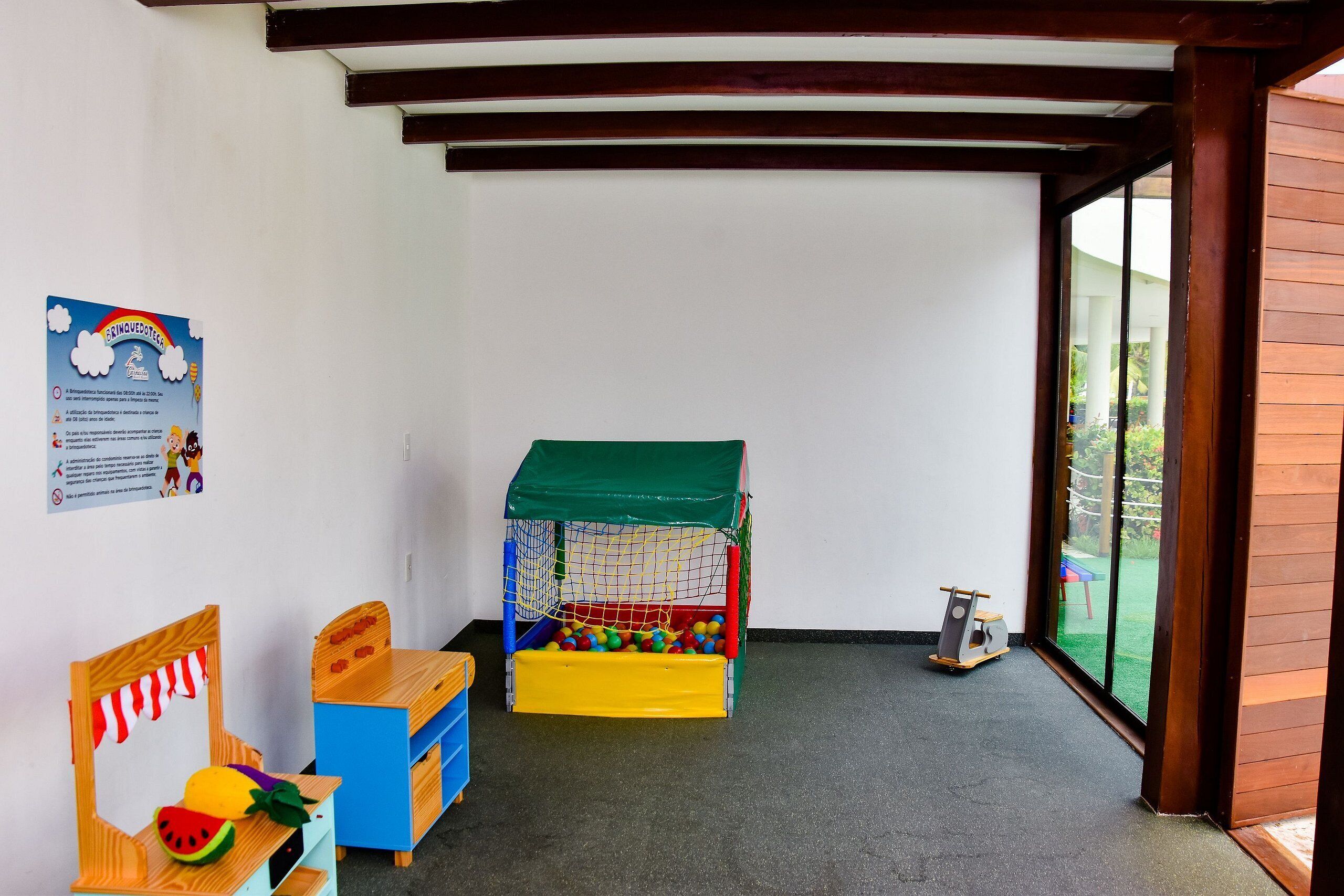 Uma área de recreação com piscina de bolinhas, uma mesa pequena e uma cadeira.