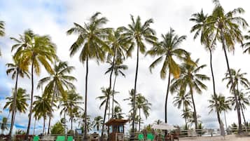 Na praia, areia branca, guarda-sóis