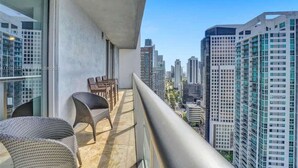 Een balkon met rieten stoelen en uitzicht op hoogbouw.