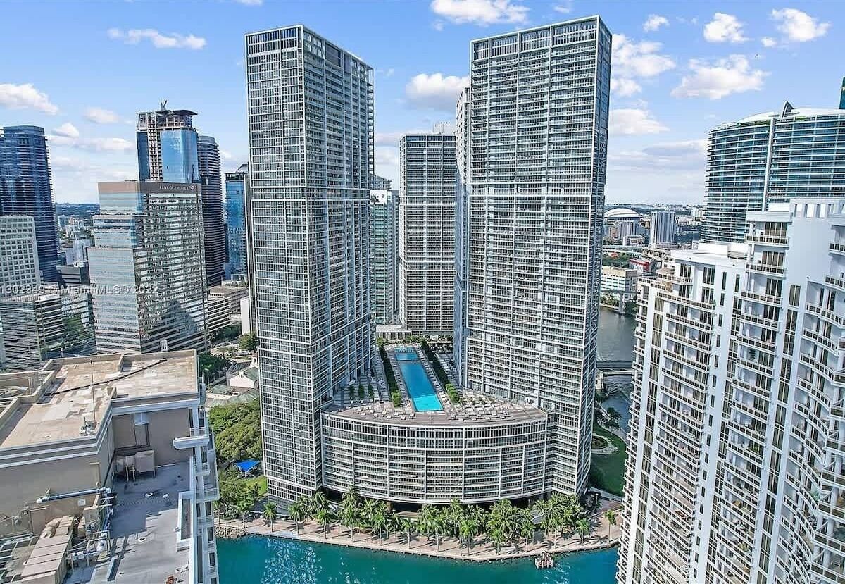 Ein Hochhaus mit einem runden Pool auf dem Dach, umgeben von Palmen.
