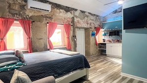 A bedroom with a bed, a sofa, a kitchenette, and a ceiling fan. - Ground floor unit With local artist mural on exterior! (Frederiksted)