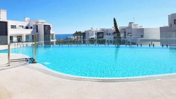 A rooftop swimming pool with clear blue water, surrounded by modern buildings and a clear sky. - Luxurious Flat With Jacuzzi and Pool at Higueron (Fuengirola)