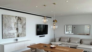 A modern living room with a wooden dining table, grey sofas, and a large abstract painting. - Luxurious Flat With Jacuzzi and Pool at Higueron (Fuengirola)
