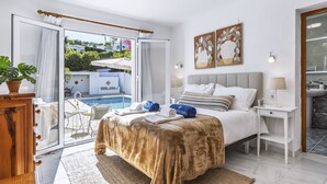 A bedroom with a bed, a nightstand, a bedside table, a large window, and a view of a swimming pool and outdoor furniture. - Casa del Limonero (Javea / Xàbia)
