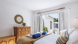 A bedroom with a bed, a wooden dresser, a mirror, and a view of an outdoor area with umbrellas. - Casa del Limonero (Javea / Xàbia)