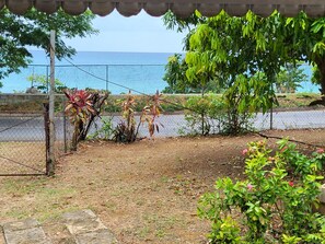 Enjoy a peaceful retreat with a garden view of the sea, surrounded by lush plants and a shaded seating area.