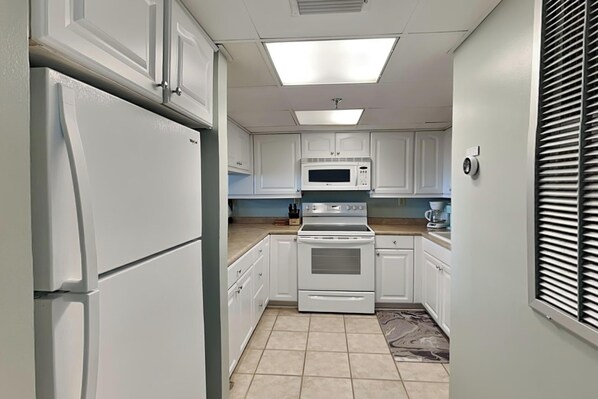 A kitchen with white cabinets, a refrigerator, a microwave, and an oven.