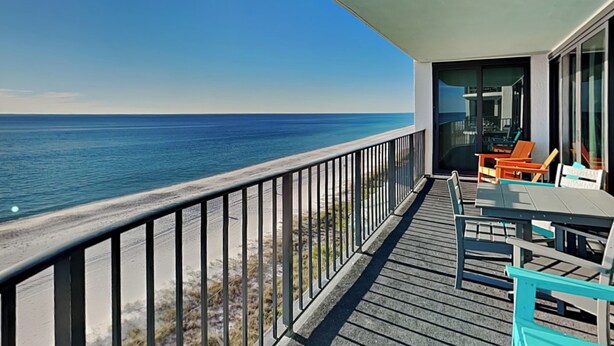 A balcony with a view of the ocean, a table with chairs, and a glass door leading to an interior space. - Watercrest #807 by Resort Collection (Panama City Beach)