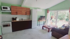A compact living space with a kitchenette, a dining area, and a sofa. - Location à la Semaine (Néoules)