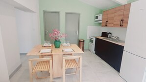 A compact kitchen with a dining table, chairs, a microwave, and a Siemens refrigerator. - Location à la Semaine (Néoules)