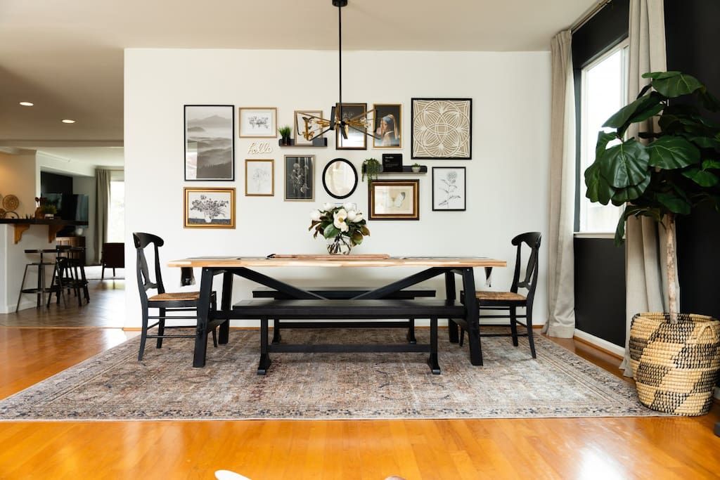 Un comedor con una mesa y sillas de madera, un tapete y decoración en la pared.