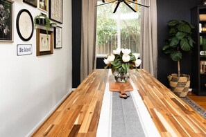 Un comedor con una mesa de madera, una obra de arte enmarcada en la pared y un jarrón con flores.
