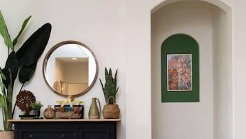 Una habitación con un mueble negro, un espejo y un cuadro con marco verde en la pared.
