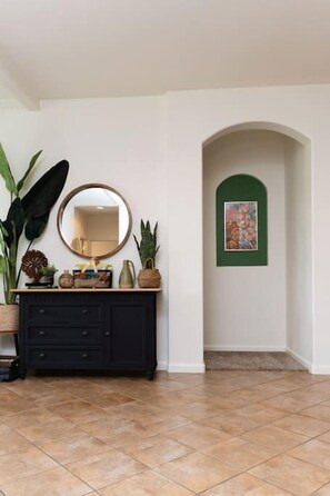 Une pièce avec un meuble noir, un miroir et un tableau encadré de vert accroché au mur.