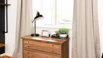 Une pièce comprenant une commode en bois, une lampe de bureau, une petite plante et une chaise.