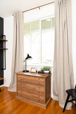 Una habitación con un aparador de madera, una lámpara de escritorio, una planta pequeña y una silla.