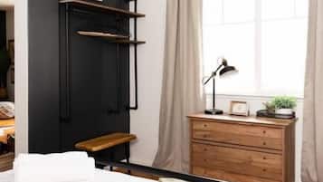 Un dormitorio con cama, mesita de noche, cómoda, ventana con cortinas y estante en la pared con una planta.