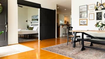 Une pièce avec un plancher en bois, une table à manger avec des chaises, une porte coulissante noire et un mur orné de tableaux encadrés.