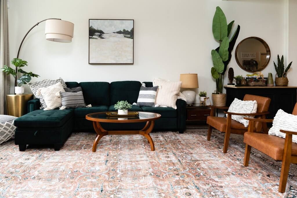 Een woonkamer met een hoekbank, een ronde salontafel en een kamerbreed tapijt.