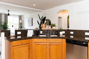 A kitchen with wooden cabinets, granite countertops, a dishwasher, and various kitchen appliances.
