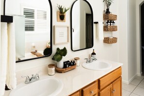 Un baño con dos lavamanos, un espejo y una planta en maceta.
