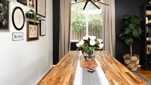 Een eettafel met een vaas witte bloemen, een kunstwerk aan de muur en een bord met de tekst 'Be kind'.