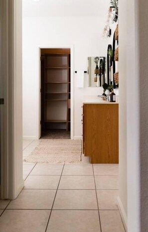 A hallway with a wooden cabinet, a tiled floor, and a door leading to a closet.