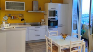 Una cucina moderna con mobili bianchi, forno integrato e zona pranzo con tavolo e sedie.