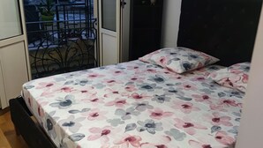Una camera da letto con un letto, un armadio e una porta scorrevole in vetro che si apre su un'area esterna con un tavolo e sedie.