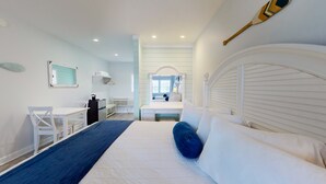 A bedroom with a bed, a desk, a chair, a mirror, and a window. - The Cape (Cape May)