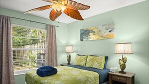 A bedroom with a bed, two bedside lamps, a ceiling fan, a window with curtains, and a painting on the wall. - Pool, Private Yard, Grill, Massage Bed Within 2 miles of USF, Moffit Center (Temple Terrace)