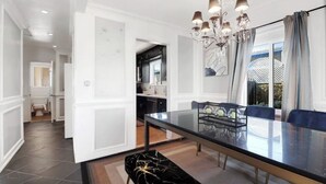 A dining area with a glass table, black and gold bench, and a chandelier. - 7mins LAX/Beach - Gorgeous Home (Hawthorne)