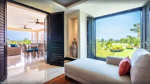 A modern bedroom with a large window offering a view of a lush garden and a pool. - Punta Mita Resort (Punta de Mita)
