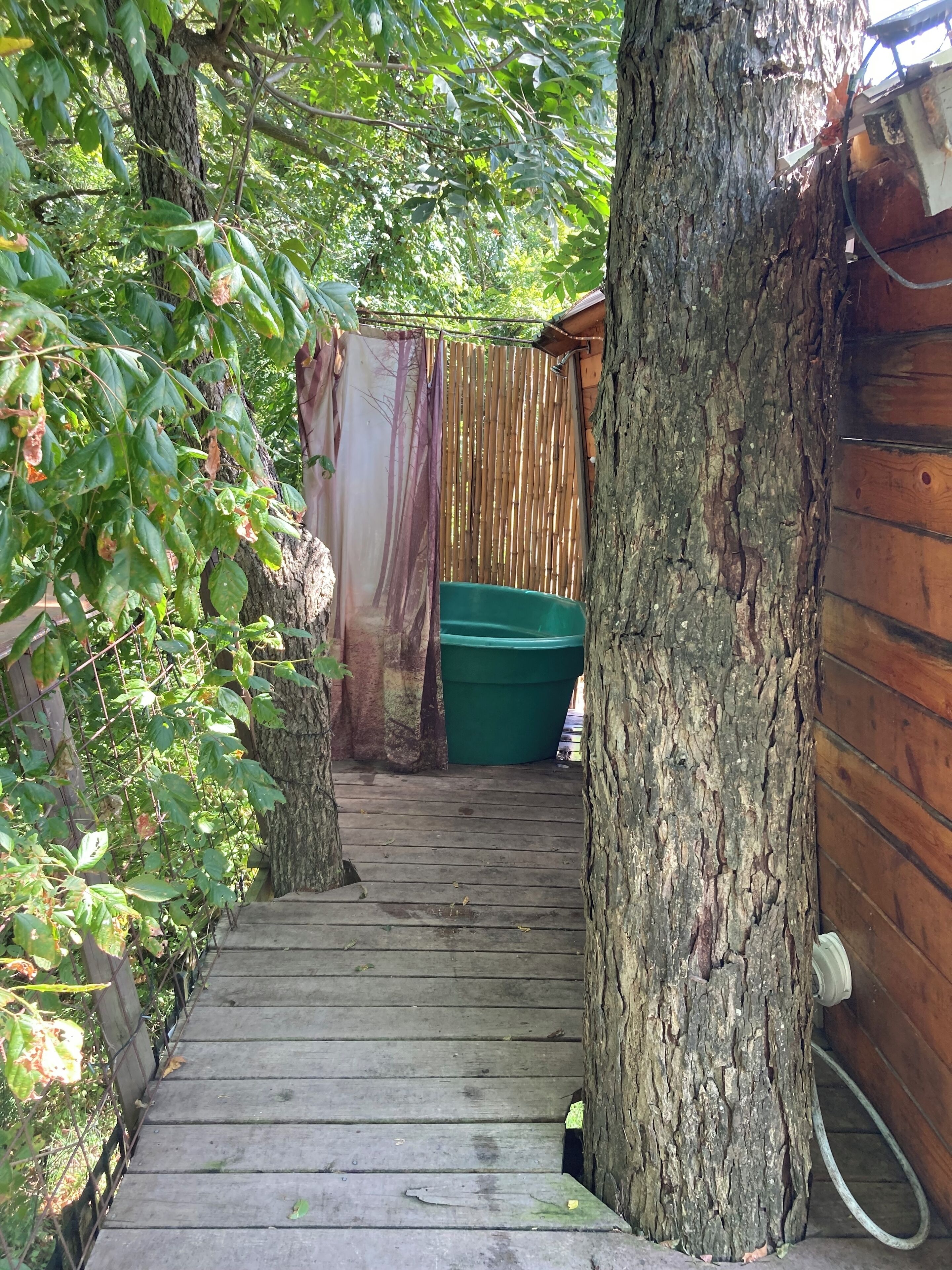 A wooden staircase leading to a covered area with a green container and a hose.