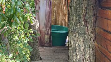 A wooden staircase leading to a covered area with a green container and a hose.